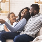 Young parents and daughter relax together on the couch. 